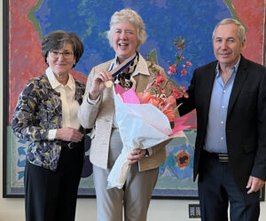 JoAnn Pushkin, Dr. Wendie Berg, and Dr Daniel Lehrer with Dr. Berg and her SBI Gold Medal on stage with flowers.
